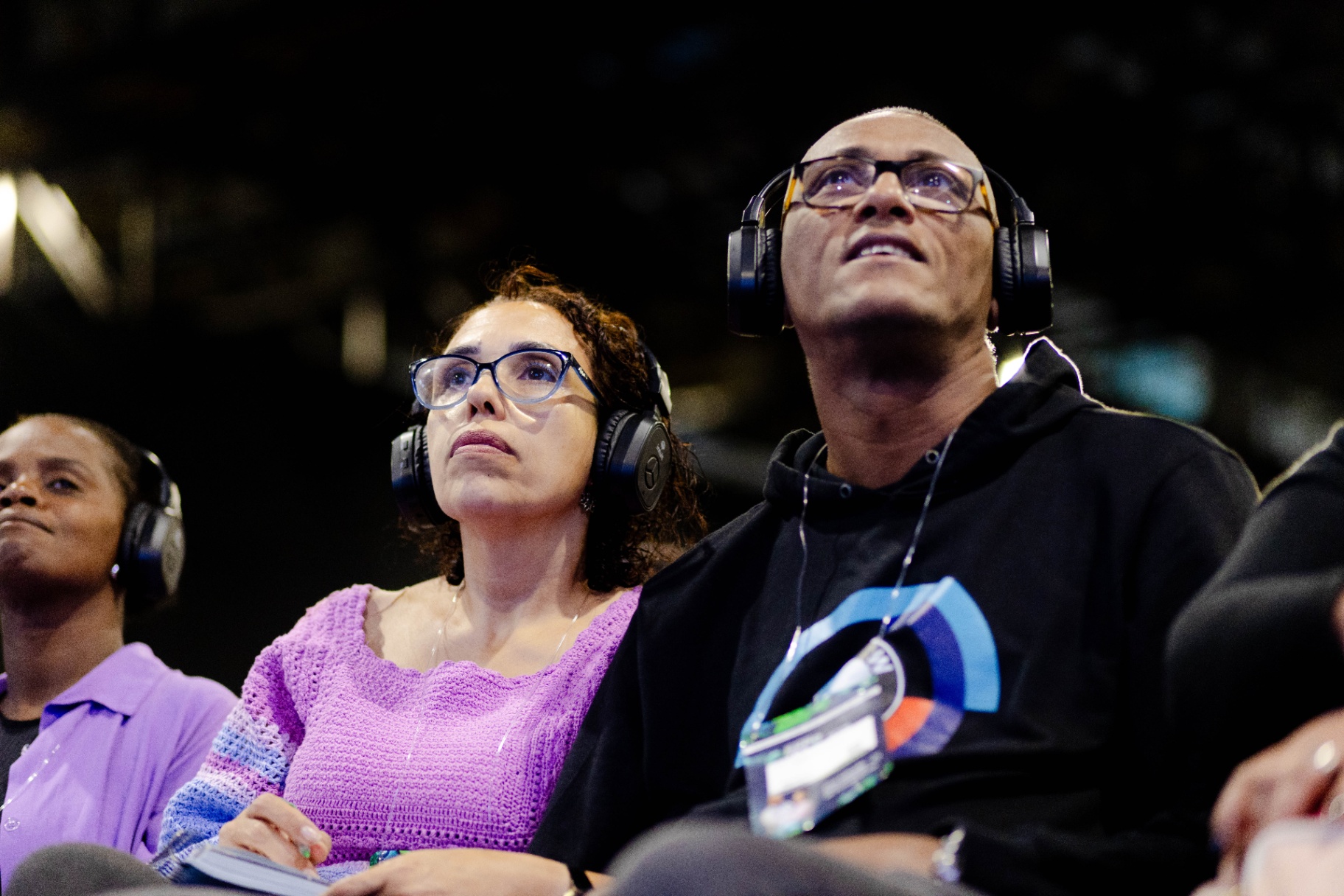 Casal de pais atentos com fones acompanhando palestra