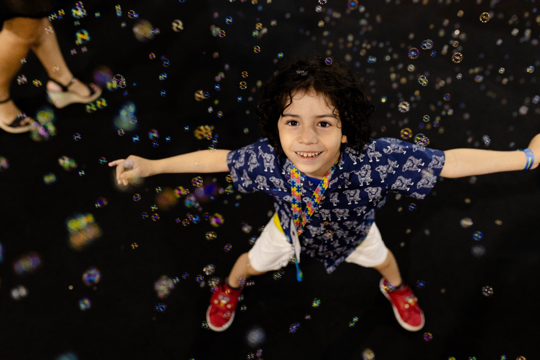 Criança sorrindo no espaço sensorial com bolhas de sabão